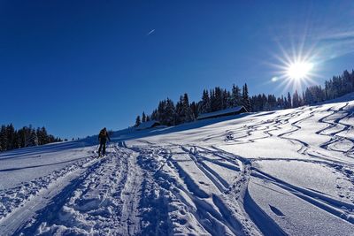 Person skiing on snow covered field against sky