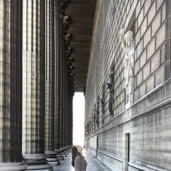 Side view of woman looking at historic building while standing in corridor 