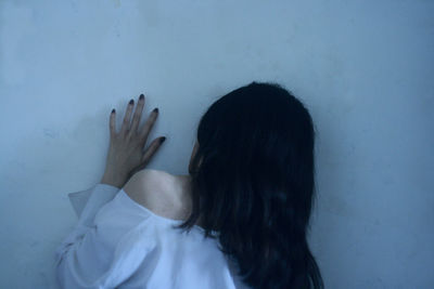 Rear view of woman touching wall
