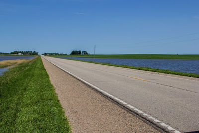 Road amidst field against clear sky