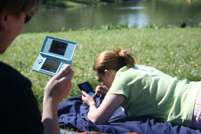 Friends playing video games while relaxing in park