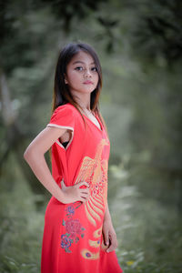 Portrait of young woman standing against trees