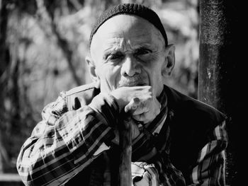 Portrait of senior man sitting against trees