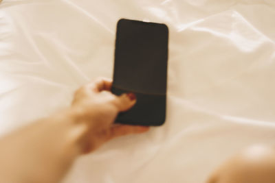 Midsection of man using mobile phone on bed