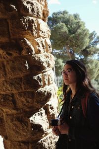 Woman standing by rock against trees