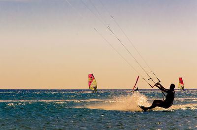 Man kiteboarding on sea against sky during sunset