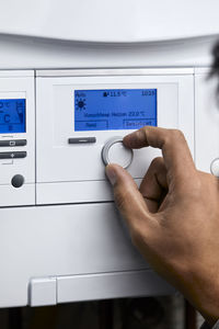 Man adjusting heating boiler with control knob at home