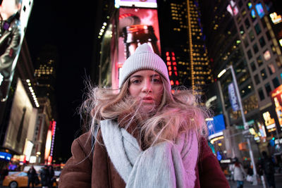 Portrait of young woman in illuminated city at night