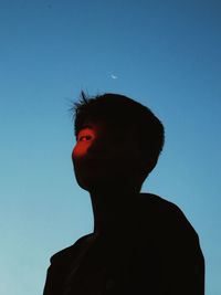 Low angle portrait of silhouette man standing against clear blue sky