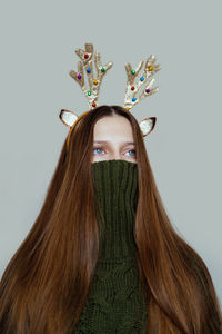 Surreal christmas portrait of a girl in a green sweater and antlers