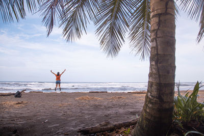 Woman jumping at beach against sky