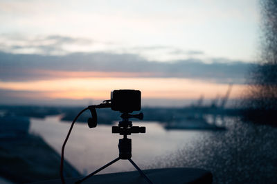 Camera taking photo on tripod against sky during sunset