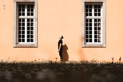 Side view of man standing on field against building