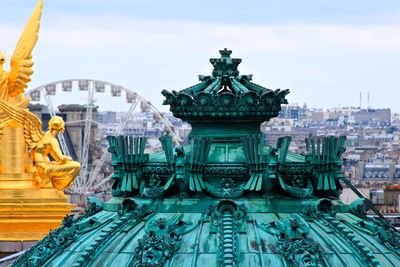 Gilded statue and dome of palais garnier against sky