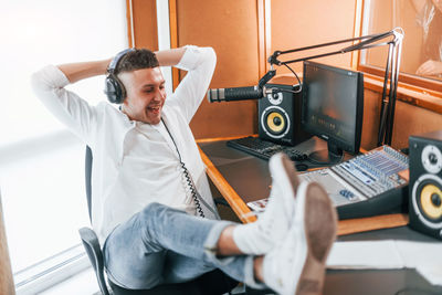 Talks and uses mic. young man is indoors in the radio studio is busy by broadcast.