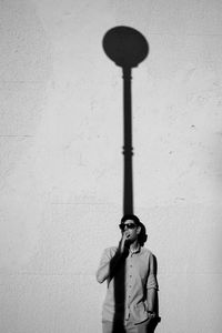 Young man smoking while standing on wall during sunny day