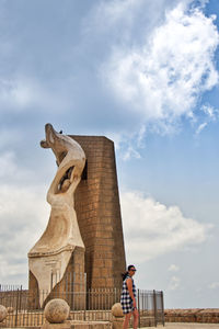 Low angle view of statue against sky and women looking