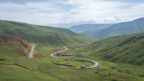 Mountain pass with curving road leading through green mountainous landscape, tien shan, kyrgyzstan