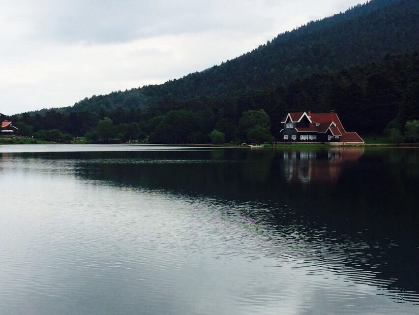 water, mountain, building exterior, architecture, built structure, waterfront, lake, house, reflection, tree, sky, tranquil scene, tranquility, scenics, mountain range, river, beauty in nature, nature, idyllic, outdoors