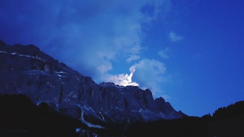 Low angle view of snowcapped mountains against blue sky