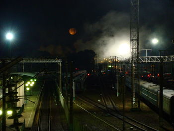 Illuminated railroad tracks in city at night