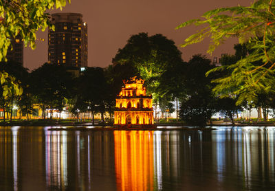 Illuminated building by lake at night