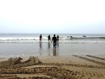 Friends on beach against clear sky