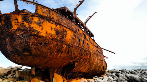 Low angle view of rusty ship against sky