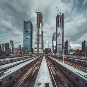 Railroad tracks amidst buildings in city against sky