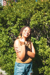 Portrait of smiling young woman standing against plants