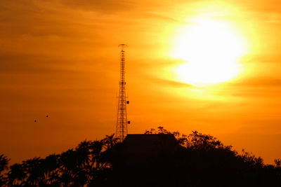 Low angle view of silhouette tower against orange sky