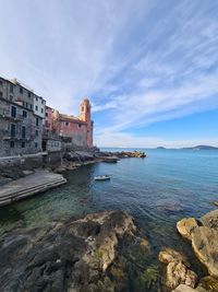 Sea by buildings against sky