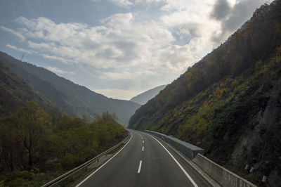 Road amidst mountains against cloudy sky