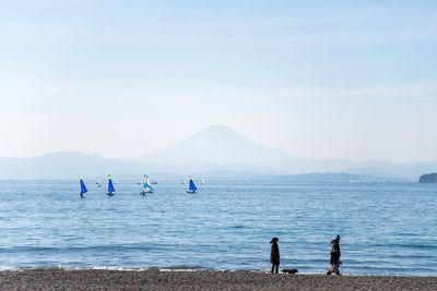 People standing at beach against sky