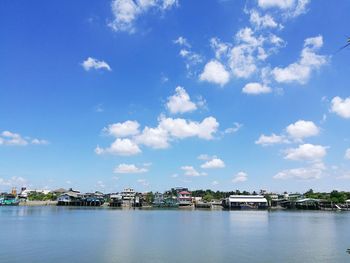 Lake by houses against blue sky