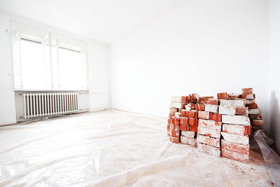 Bricks arranged by wall against radiator at home