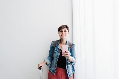 Smiling woman standing against wall