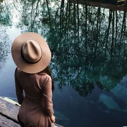 Rear view of shirtless man standing by lake