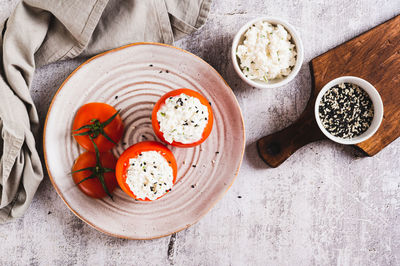 Fresh tomatoes filled with cottage cheese and herbs on a plate on the table top view