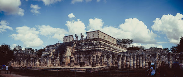 Panoramic view of tourists against cloudy sky