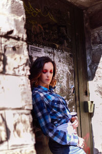 Beautiful young woman posing while standing against wall