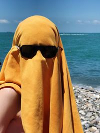 Close-up of sunglasses on beach against sky