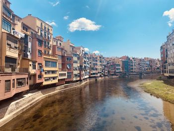 Canal amidst buildings in city against sky