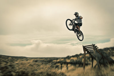 Man performing stunt on bicycle against sky