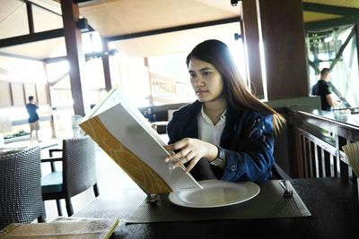 Woman reading menu while sitting at restaurant