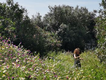 Full length of woman standing by flowering tree