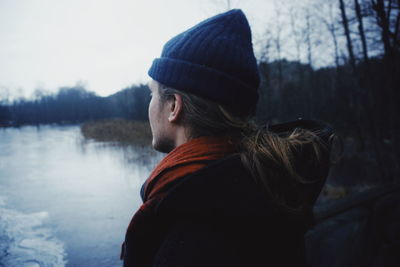 Rear view of man in river against sky during winter