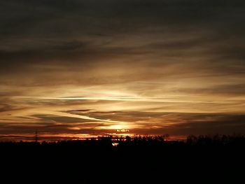 Silhouette landscape against dramatic sky during sunset