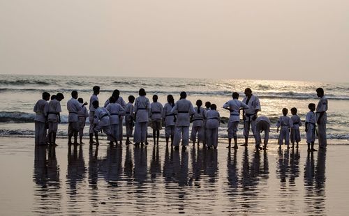 Group of people at beach against clear sky