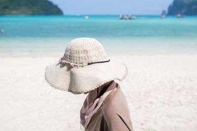 Woman wearing hat on beach against sea